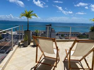 two chairs on a balcony with a view of the ocean at Casa Versace Salvador - Colonial House in Salvador