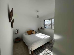 a white bedroom with a bed and a window at La Villa Case-Bi in Saint-Germain-sur-Ay