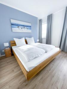 um quarto com uma cama grande e lençóis brancos em Ferienwohnung auf dem Hof Postma em Lambrechtshagen