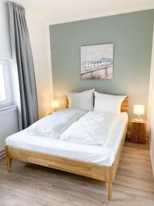 a bed with white sheets and pillows in a bedroom at Ferienwohnung auf dem Hof Postma in Lambrechtshagen