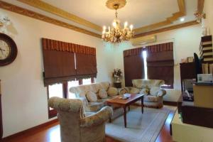 ein Wohnzimmer mit Sofas, einem Tisch und einer Uhr in der Unterkunft Bertam Villa Suites - Golf Resort by RZAC in Kepala Batas