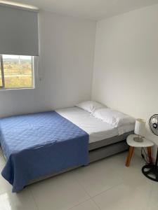 a white bedroom with a bed and a window at Bonito apto Neiva in Neiva