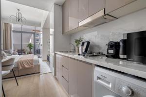 ドバイにあるGuestReady - Urban Retreat in Downtownの白いキャビネット付きのキッチン、ベッド1台が備わる客室です。