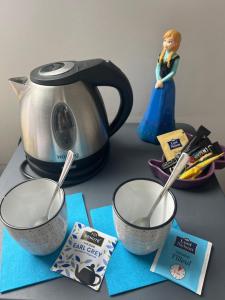 una mesa con dos tazas de medición y un hervidor de agua en Chambres d'Hôtes Poirier Bazin, en Montry