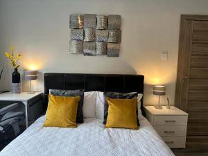 a bedroom with a bed with yellow pillows at A luxury double bedroom with ensuite in High Wycombe in Buckinghamshire