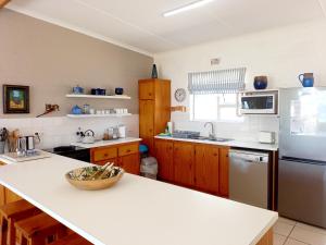 cocina con encimera blanca y armarios de madera en Beach Haven Cottage, en Britannia Bay