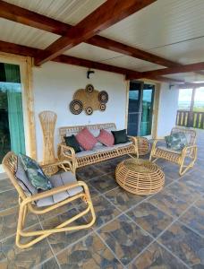 een patio met rieten stoelen en een auto aan de muur bij Pura - Home in Nature in Oliveira do Hospital