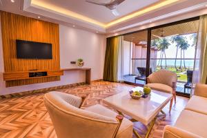 ein Wohnzimmer mit einem TV, einem Tisch und Stühlen in der Unterkunft Silver Sand Sea Princess Beach Resort in Manglutān