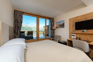 a bedroom with a bed and a desk and a large window at Nira Alpina in Silvaplana