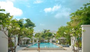a woman walking by a pool at a resort at Elysium Suite in Siem Reap