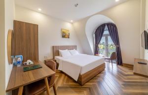 a hotel room with a bed and a table and a desk at Tala Dalat Hotel in Da Lat