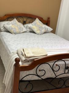 ein Bett mit weißer Bettwäsche und Kissen darauf in der Unterkunft Cozy Quarters Tobago in Scarborough