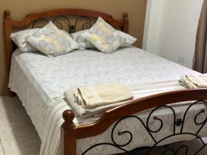 ein Bett mit einem Holzrahmen und Kissen darauf in der Unterkunft Cozy Quarters Tobago in Scarborough
