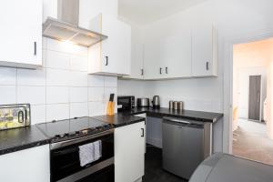 a kitchen with white cabinets and black counter tops at 3 Bedroom Apartment in Southchurch Village in Southend-on-Sea