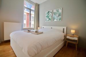 ein Schlafzimmer mit einem weißen Bett und einem Fenster in der Unterkunft Heart of Grand Place - Stunning 2BR Duplex in Brüssel