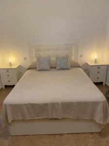 una camera da letto con un grande letto con due comodini di Apartamento San jose a Jerez de la Frontera