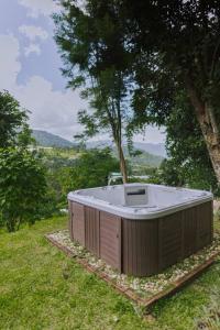 a hot tub sitting in the grass next to a tree at Muangkham Cabin in Chiang Mai