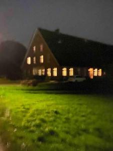 a large house with lights on in a green field at Vierländer Hippiehof in Hamburg