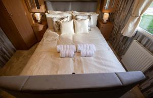 a large bed with two mens towels on it at Tattershall VIP Retreat - Hot tub, stunning lakeside views, newly refurbished to an amazing 5 star standard in Tattershall