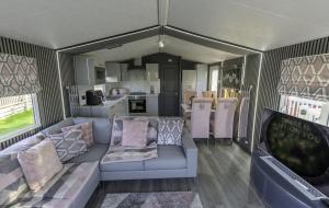 an rv living room with a couch and a kitchen at Tattershall VIP Retreat - Hot tub, stunning lakeside views, newly refurbished to an amazing 5 star standard in Tattershall