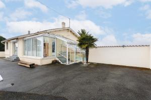 a house with a palm tree in a parking lot at Maison Boyardville Piscine Chauffée in Saint-Georges-dʼOléron