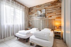 two beds in a room with a wooden wall at Maison Boyardville Piscine Chauffée in Saint-Georges-dʼOléron +13 photos