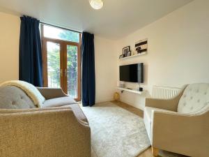 ein Wohnzimmer mit 2 Stühlen und einem Flachbild-TV in der Unterkunft Chic Haven in Barnsley in Barnsley