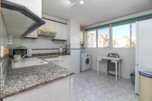 a white kitchen with a sink and a table at Apartamento Golf Pau Casals in Albir
