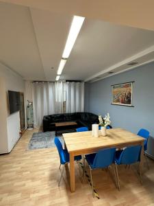 Ferienwohnung Kreuzberg في برلين: غرفة معيشة مع طاولة خشبية وكراسي زرقاء