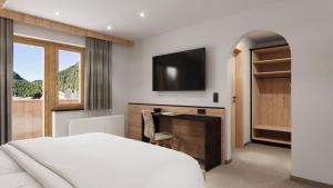a bedroom with a bed and a desk and a television at Hotel Garni Pfeifer in Ischgl