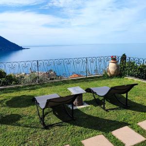 due sedie e una panchina nell'erba vicino all'acqua di Villa Mortola a Camogli