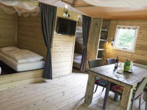 a room with a table and a bed and a bedroom at Cozy tentlodge with roofed terrace in a green area in IJhorst