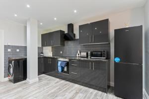 a large kitchen with black cabinets and appliances at Modern Coastal Haven in Harwich