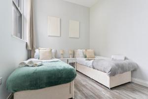 a bedroom with two beds and a green ottoman at Modern Coastal Haven in Harwich