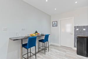 a kitchen with a table with blue bar stools at Modern Coastal Haven in Harwich