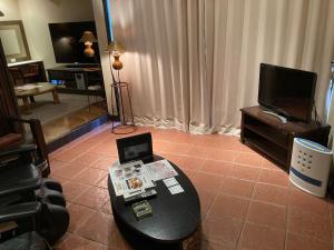 a living room with a table and a television at グッドホテル大阪 in Toyonaka
