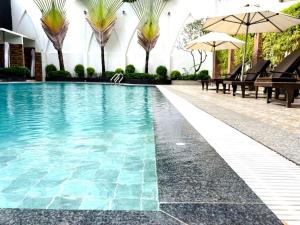 a swimming pool with benches and umbrellas in a building at Aristocrat Residence & Hotel in Sihanoukville