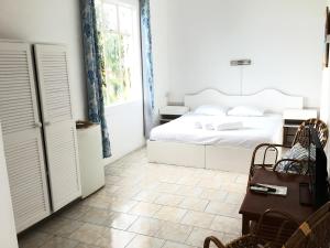 a white bedroom with a bed and a window at Villa Paille en Queue in Flic-en-Flac
