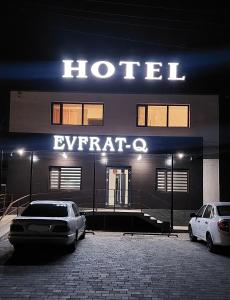 dos coches estacionados frente a un hotel por la noche en EVFRAT-Q, en Taraz
