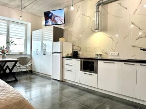 a kitchen with white cabinets and a tv on the wall at Comfortable apartments in the city center, near the theater and Zlata Plaza in Rivne