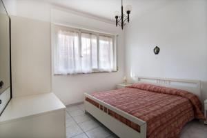 ein weißes Schlafzimmer mit einem Bett und einem Fenster in der Unterkunft Appartamenti NA in Follonica
