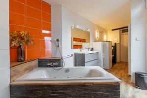 une grande baignoire blanche dans une cuisine avec du carrelage orange dans l'établissement Luxe vakantiewoning dichtbij strand in Vlissingen, à Flessingue