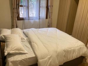 a bed with white sheets and pillows in a room at RH4A Jinja Apartment Airport in Jinja