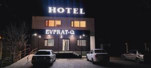 dos coches estacionados frente a un hotel por la noche en EVFRAT-Q, en Taraz