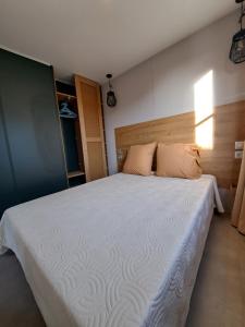 1 dormitorio con 1 cama grande con sábanas y almohadas blancas en Chalet n * 1 au cœur du maquis, en Bonifacio