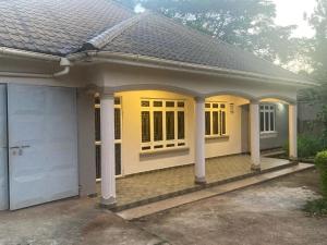 a home with a yellow front porch and columns at RH4A Jinja Apartment Airport in Jinja