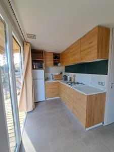 eine Küche mit Holzschränken und einem weißen Kühlschrank in der Unterkunft Chalet n * 1 au cœur du maquis in Bonifacio