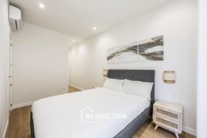 een witte slaapkamer met een bed en een schilderij aan de muur bij MyHouseSpain - Renovado y luminoso apartamento in Madrid
