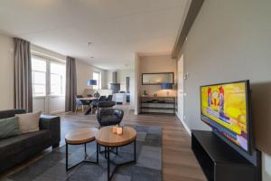sala de estar con sofá y TV en Design apartment in Zeeland with its own wellness, en Colijnsplaat