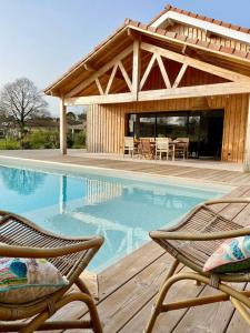 a swimming pool with two chairs and a house at Belle Villa Terra Mare classée 4 étoiles entre océan et bassin in Lège-Cap-Ferret